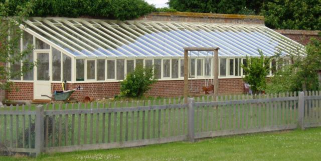 A large greenhouse which makes the most of an existing garden wall